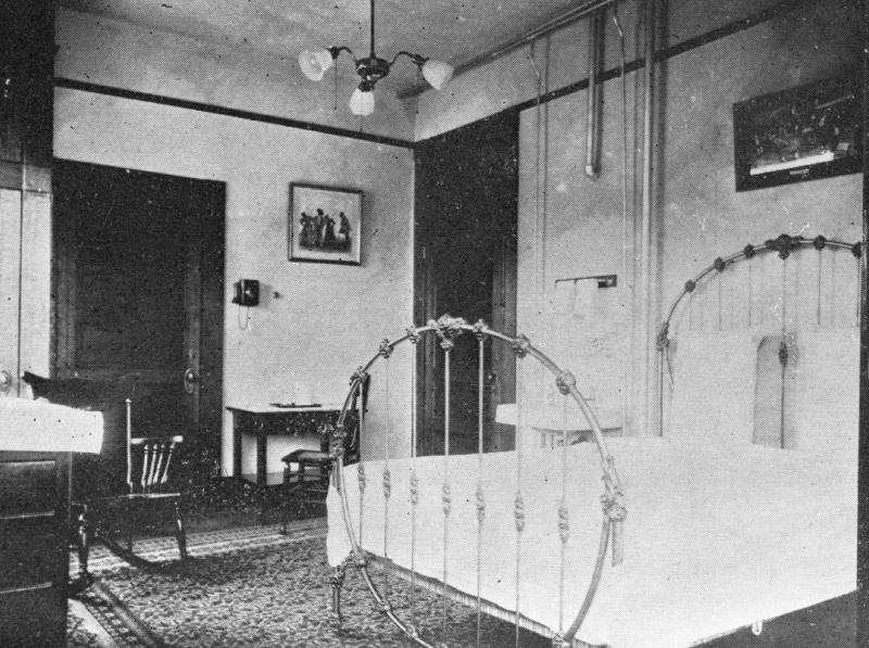 Historic photo of the Basin Park Hotel's guest rooms with a bed and a desk